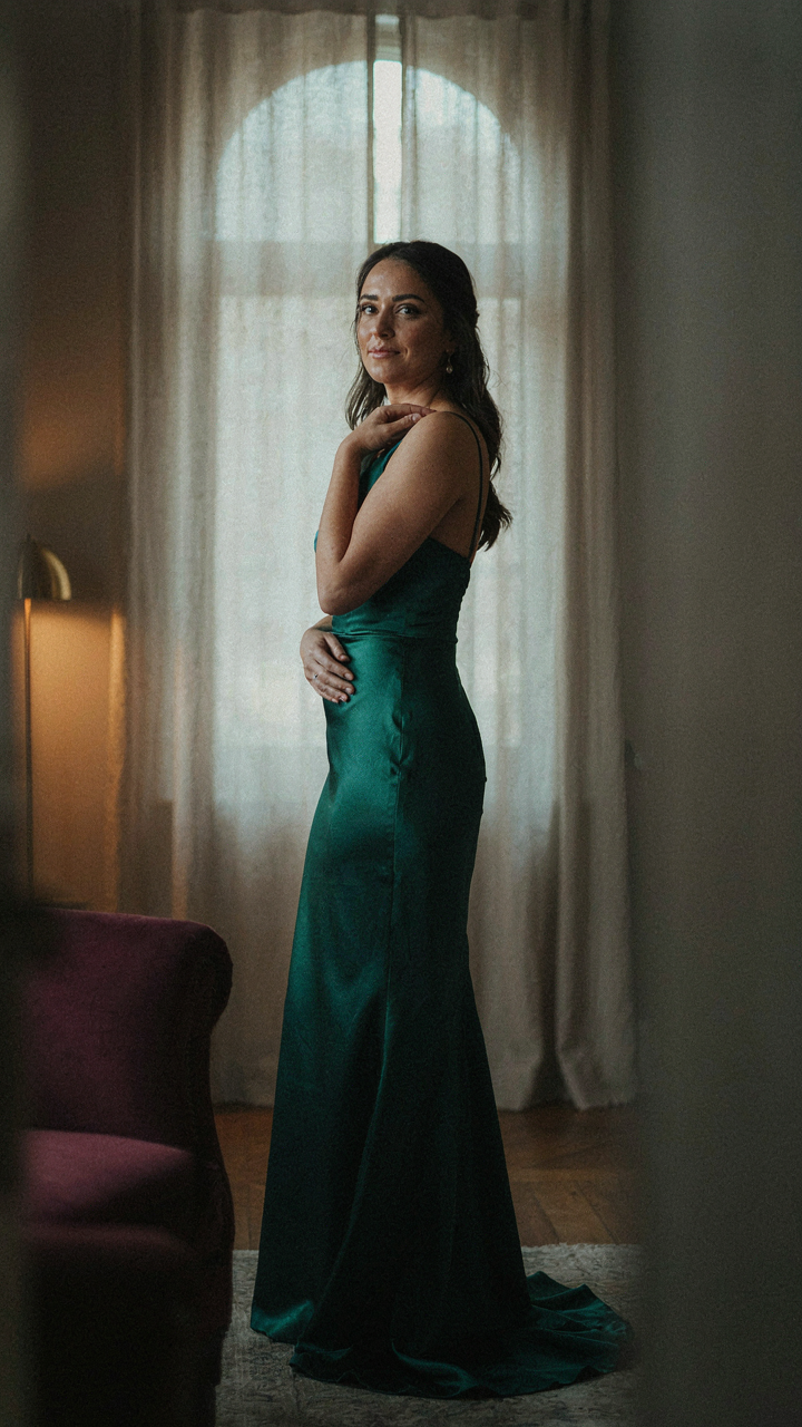 A woman in an evening gown shows a soft, genuine expression, looking away.