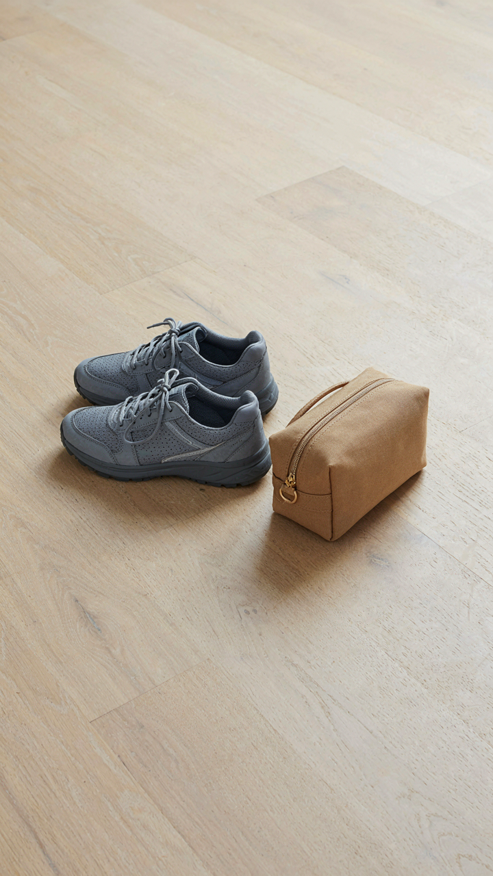 A pair of walking shoes sits next to a small, functional travel bag.