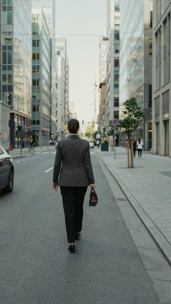 A woman in a fitted blazer walks confidently down a city street.