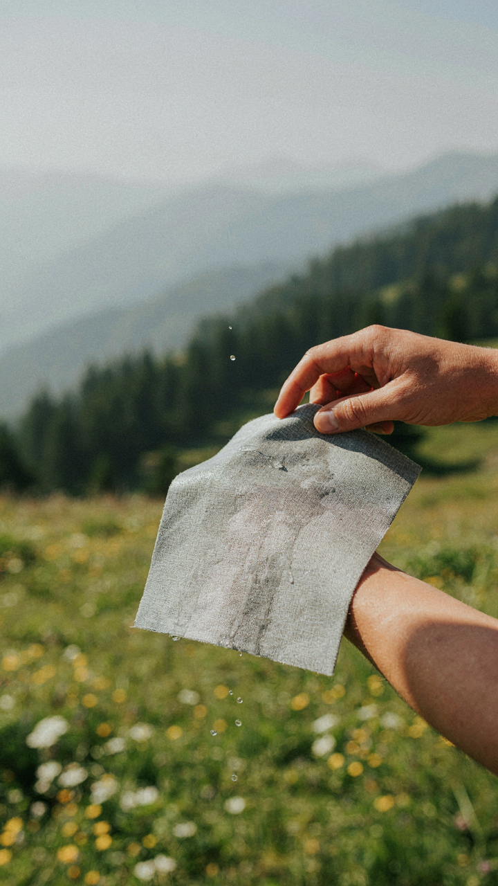 A hand tests a fabric swatch for quick drying under an arm.
