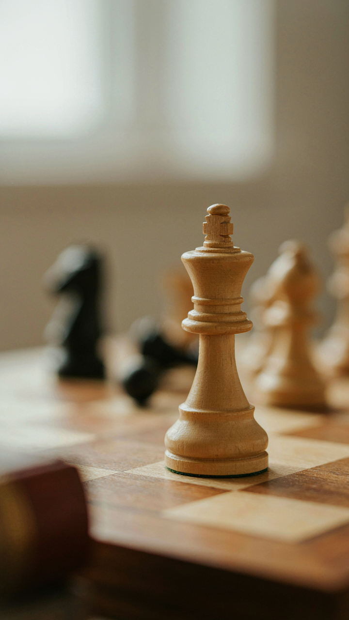 A queen chess piece stands clearly on a chess board.