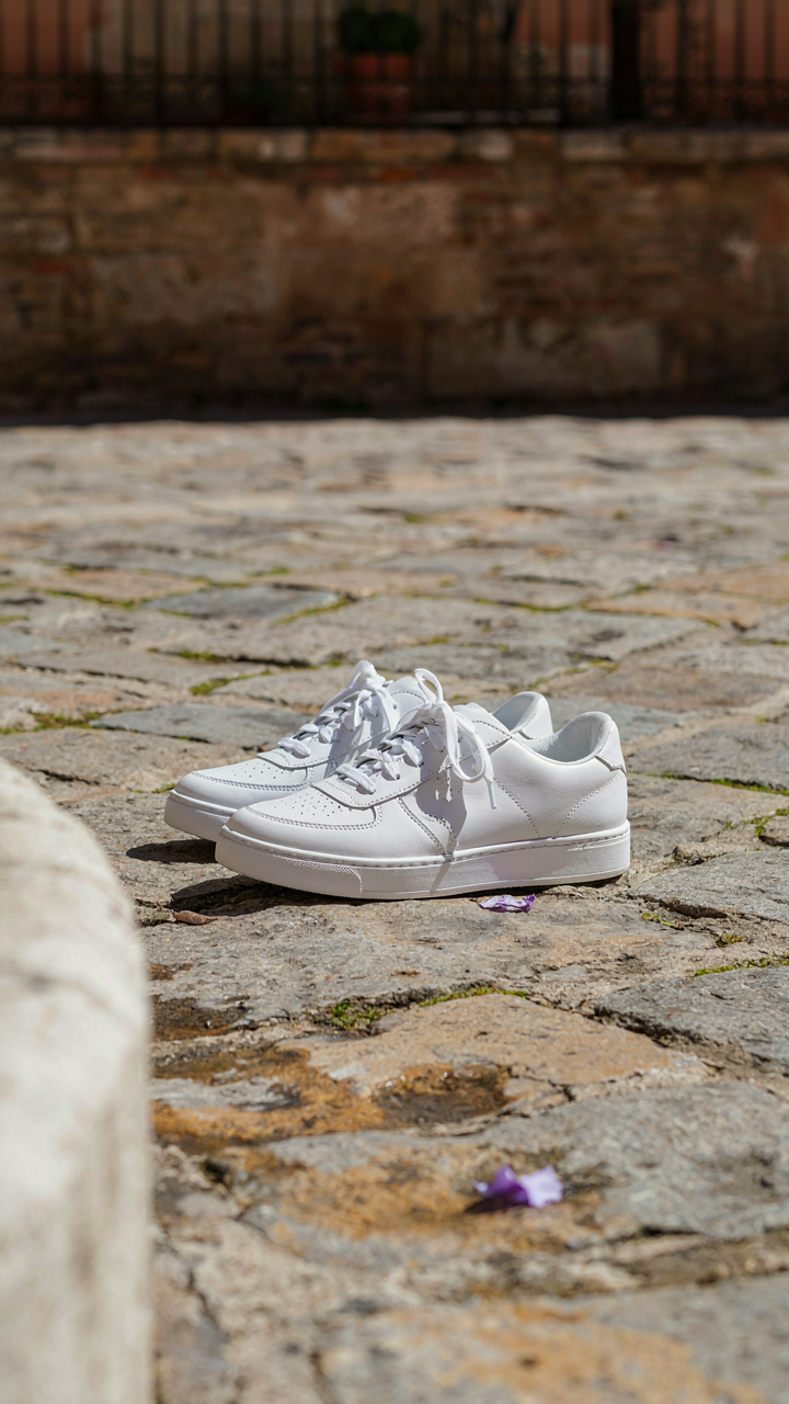 White leather sneakers on cobblestones, ready for walking in a Spanish city.