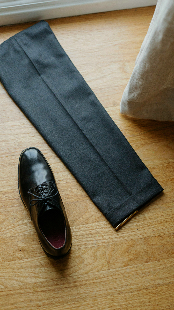 A shiny polished shoe sits next to a clean, pressed pant leg.