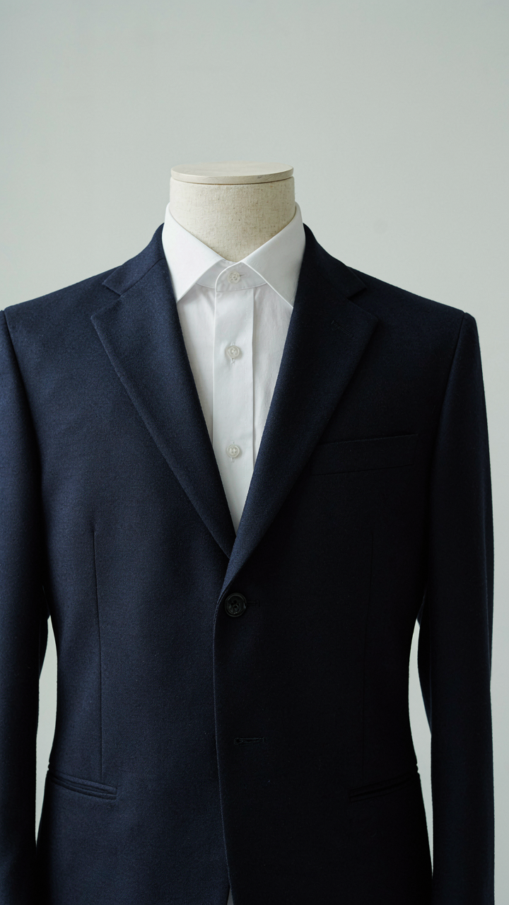 A perfectly fitted navy blue blazer with peaked lapels on a mannequin.
