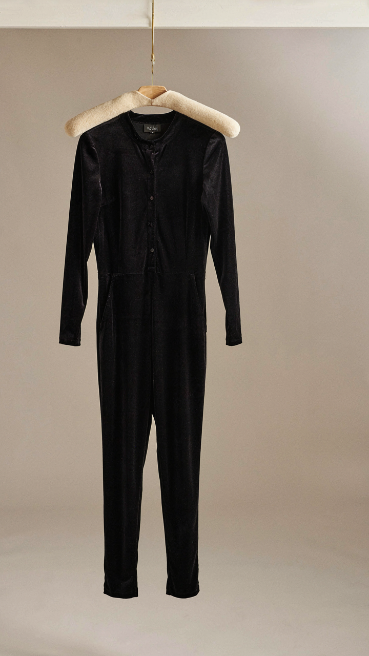 Dark velvet jumpsuit with a fitted merino wool mock neck underneath on a hanger.
