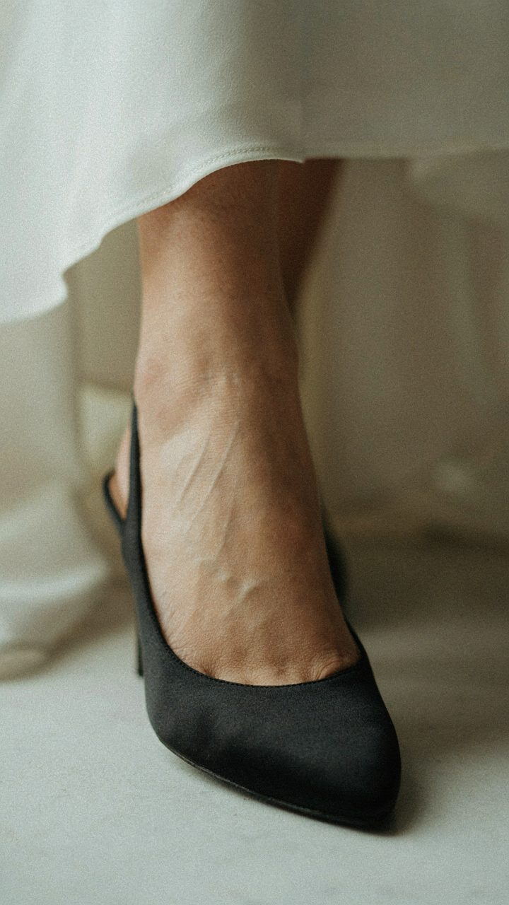 A woman's foot in a black satin slingback flat.