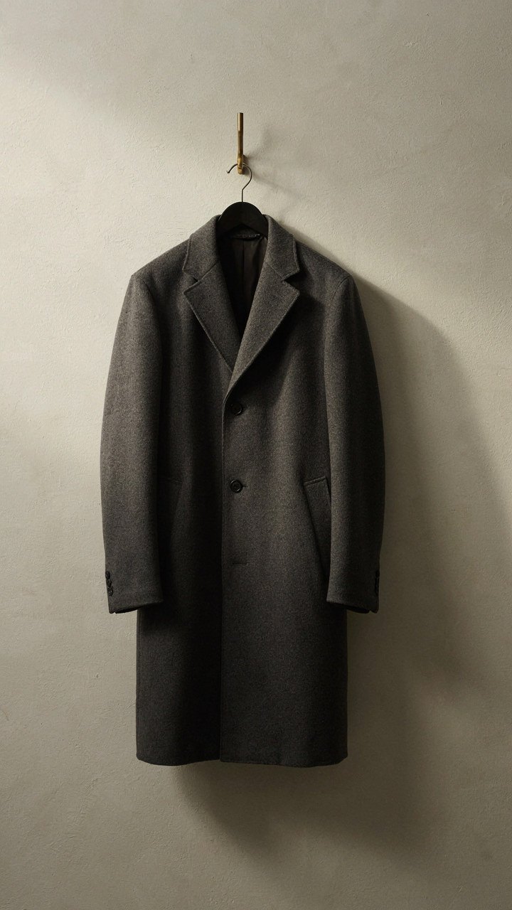 A perfectly tailored wool coat hangs on a minimalist wall hook.