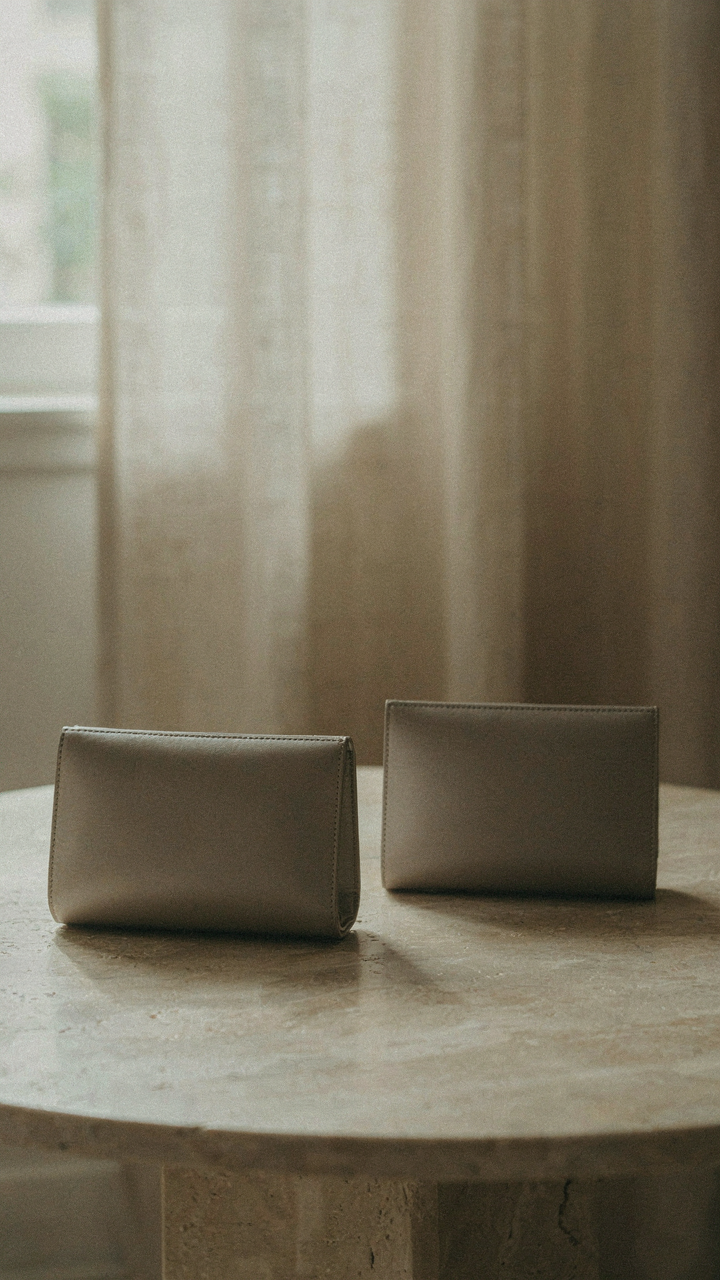 A bulging clutch sits next to a sleek, empty clutch on a table.