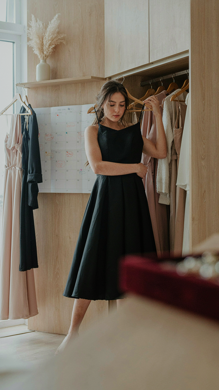 A woman choosing an a line cocktail dress from her wardrobe for a social event.