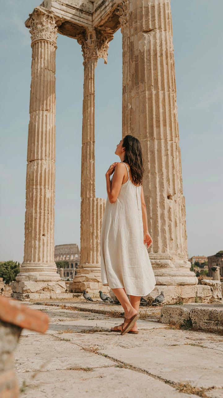 A person in comfortable clothes views ancient Roman ruins, looking relaxed.