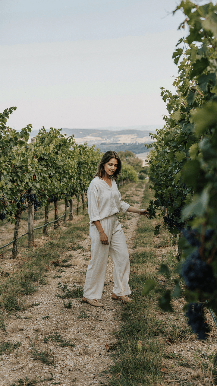 A person in a linen jumpsuit walks confidently on a vineyard path.