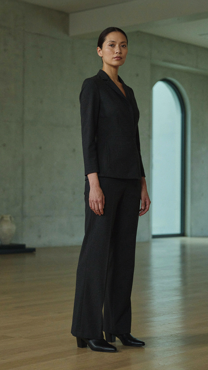 A woman wears a perfectly tailored dark wool crepe jumpsuit.