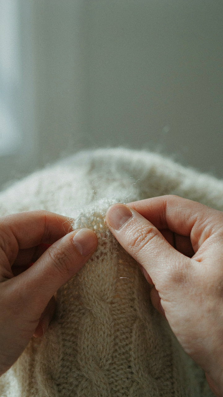 Hands examine the detailed weave of a high-quality wool sweater.