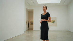 A woman in a black column dress, representing timeless evening outfits women, in an art gallery.