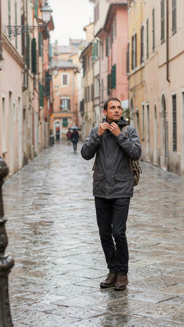 A traveler adjusts a jacket while walking, adapting to changing weather.