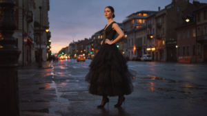 A woman wears a voluminous black tulle skirt evening outfit on a city street at dusk.