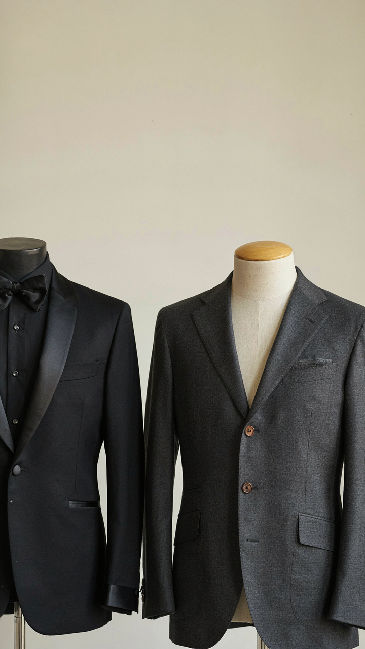 A tuxedo jacket with satin lapels next to a suit jacket.