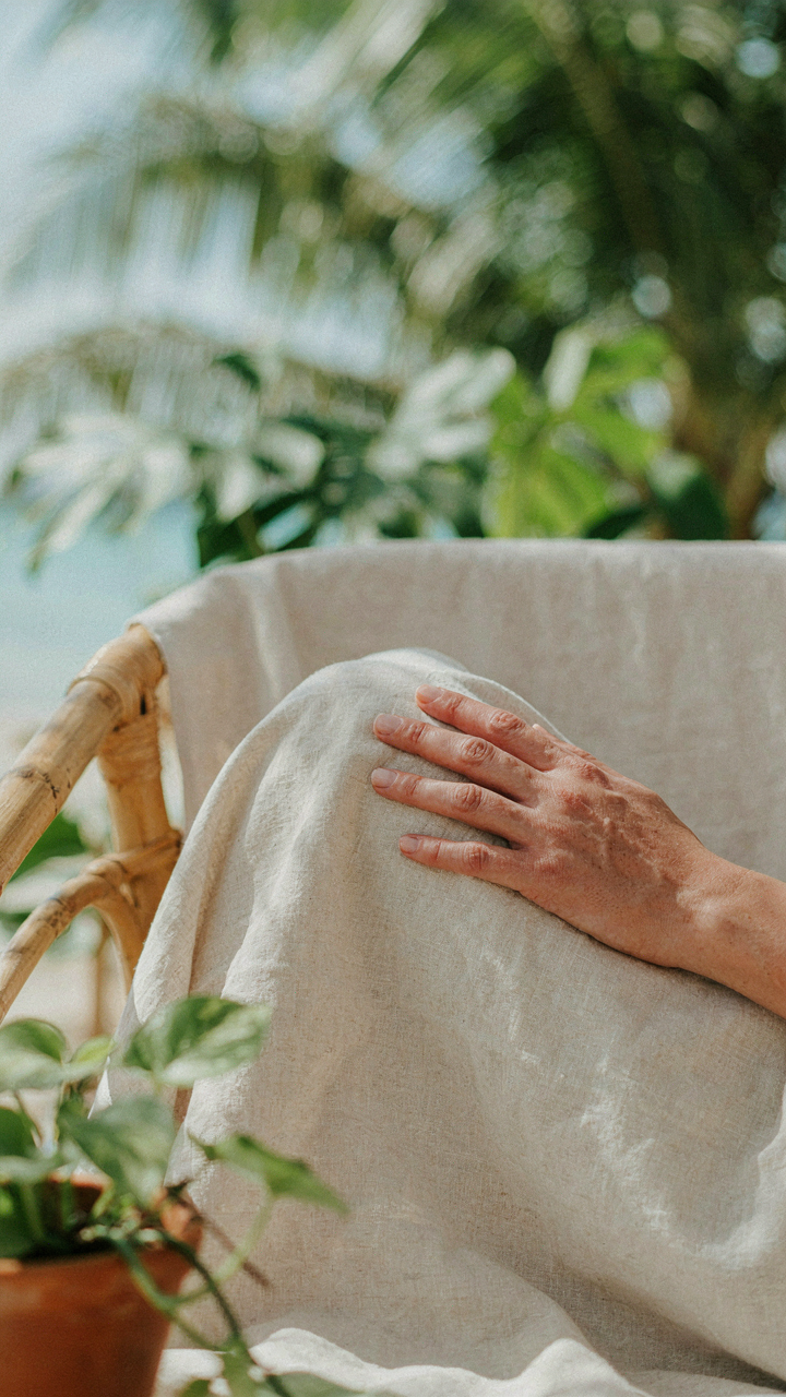 A hand touches a breathable linen fabric for warm weather attire.