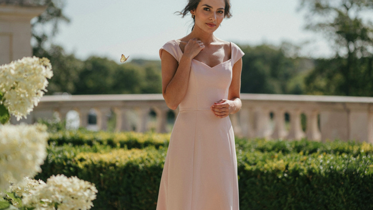 A woman confidently wearing a wedding guest dress for broad shoulders, showcasing balanced lines.
