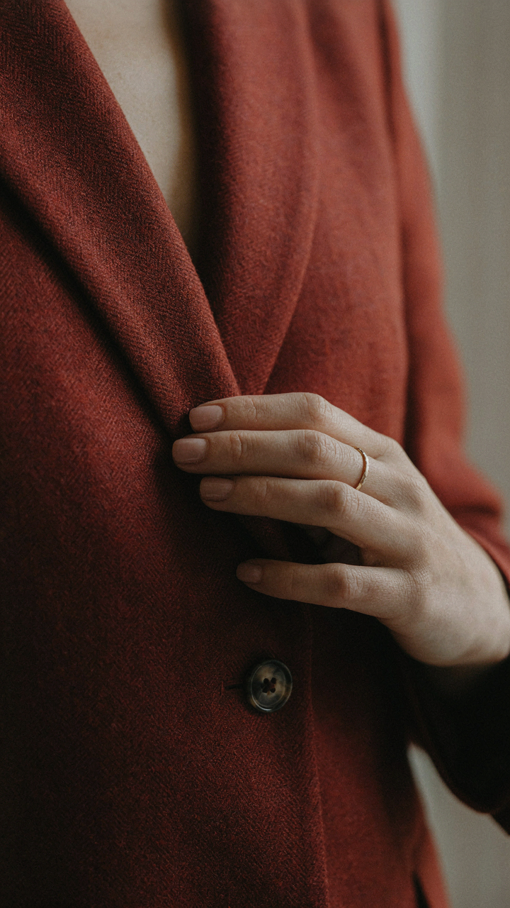 A woman's hand touches a soft, finely woven wool blazer.