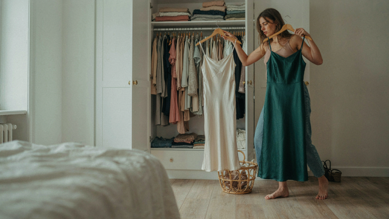 A woman looks at two dresses, trying to decide what to wear for a semi formal event.