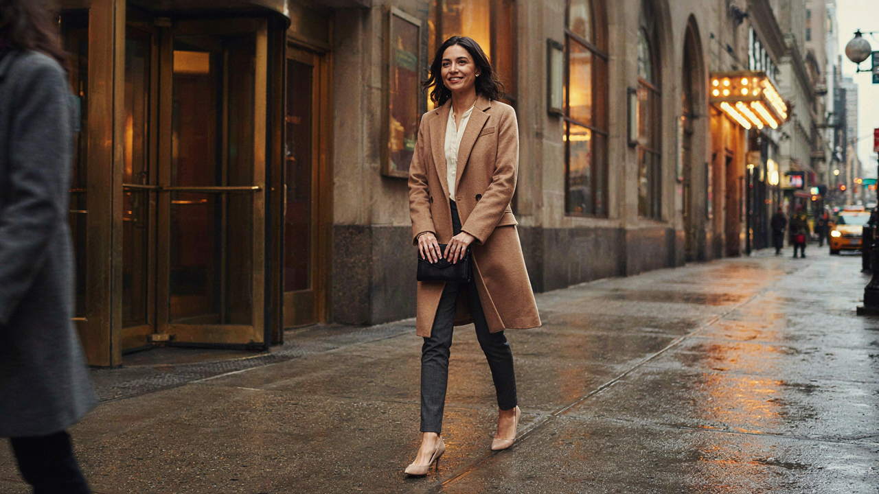 Woman in an elegant, comfortable outfit exiting a Broadway theater, smiling after a show.