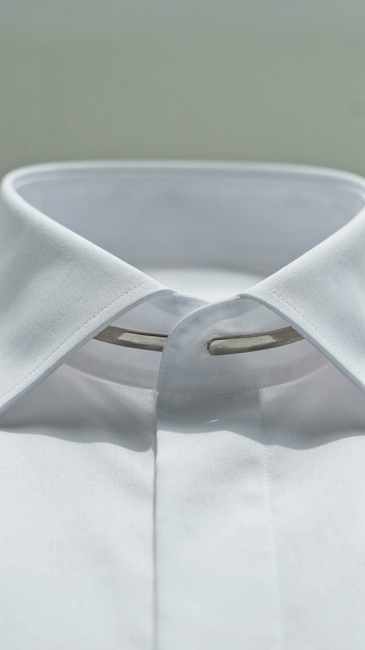 A close-up of a crisp white dress shirt collar with a visible collar stay.