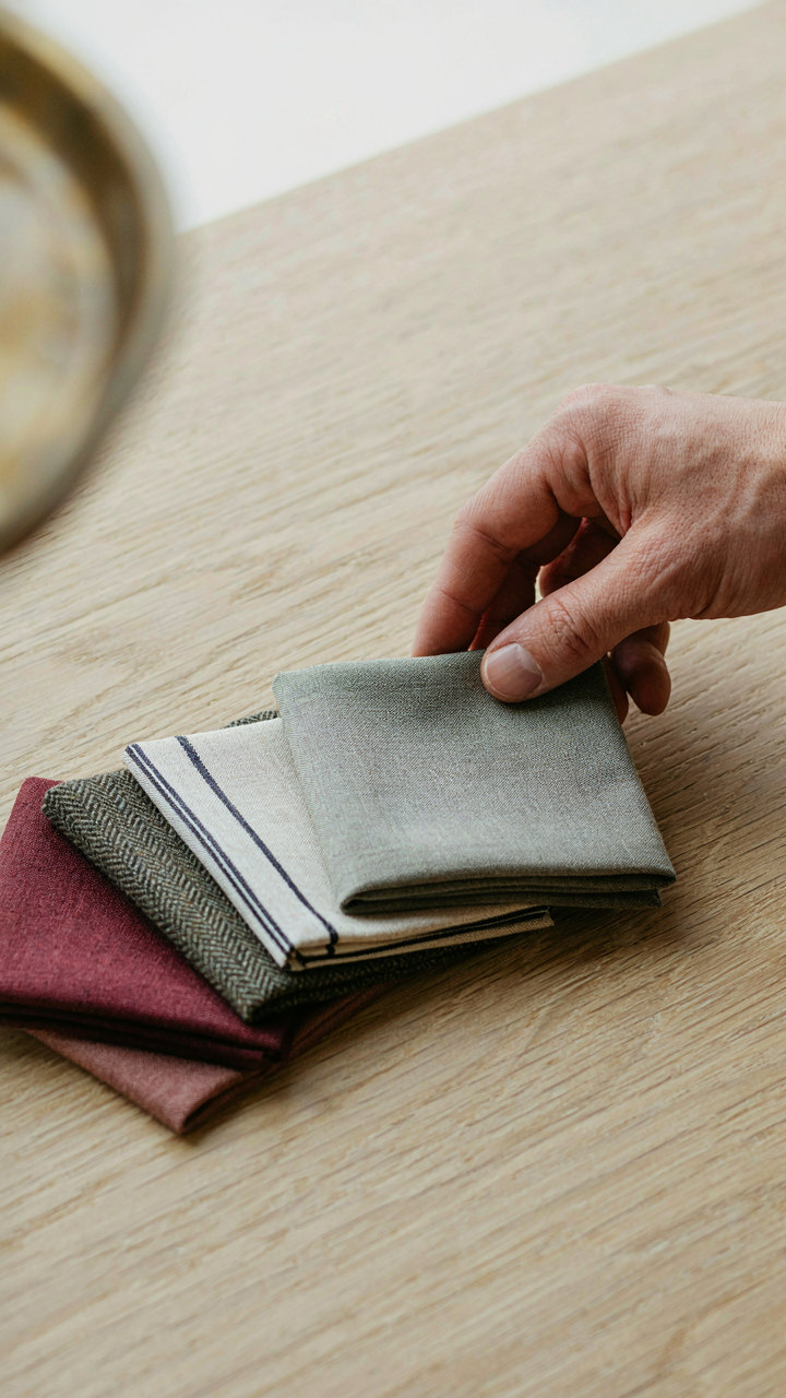 A hand carefully choosing a small, subtle pocket square.