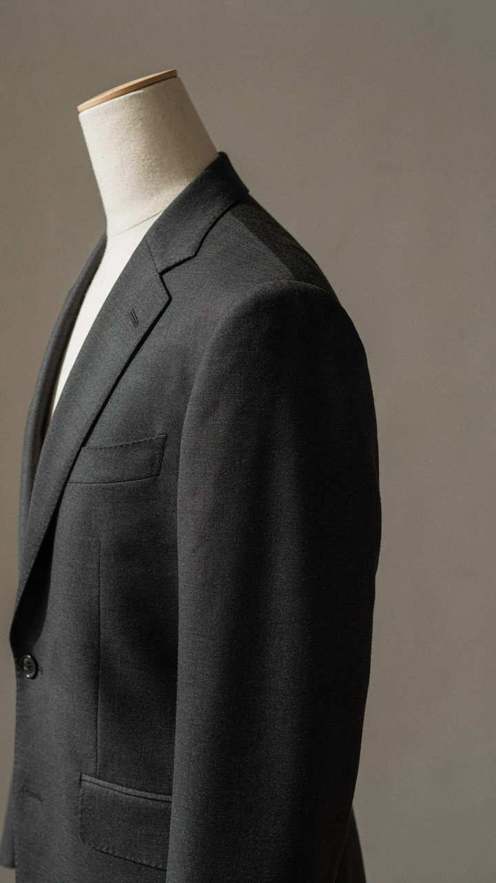 A close-up shows the precise shoulder seam of a tailored blazer.