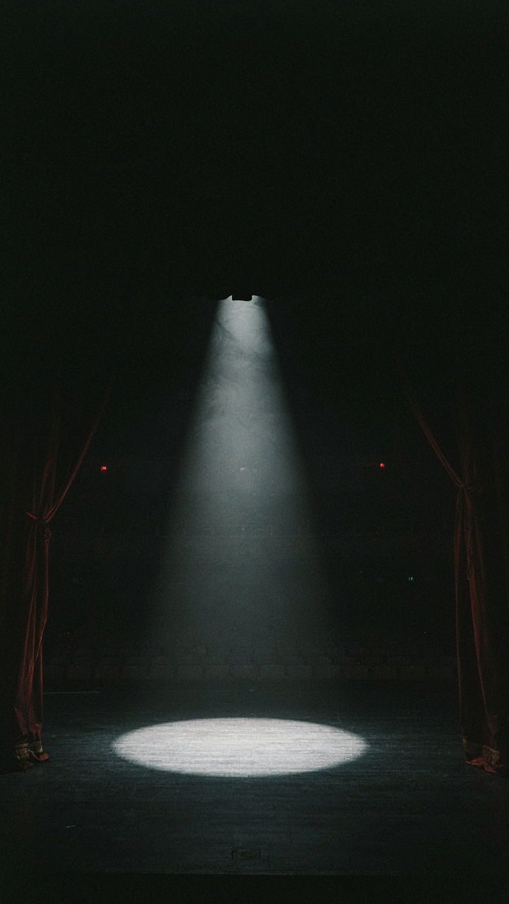 A powerful spotlight illuminates an empty stage, ready for a commanding presence.